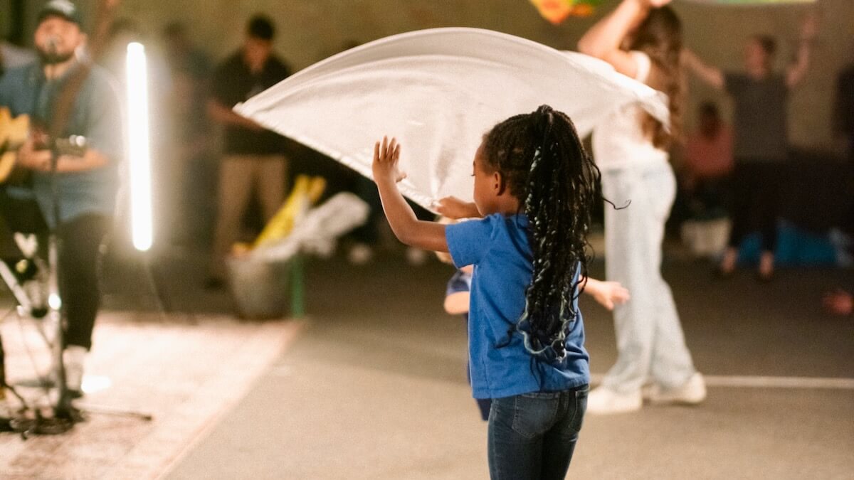 A child waving a flag in worship at Nations House of Prayer